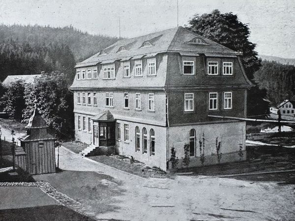 Historische Aufnahme: großes dreigeschossiges Haus mit Mansarddach, davor ein kleiner Pavillon