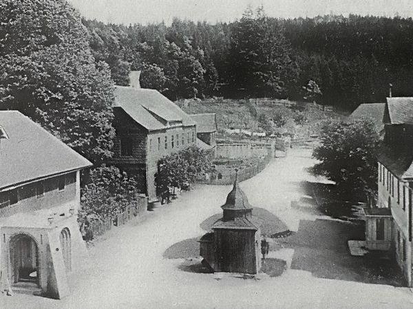 Historische Aufnahme: Blick die Dorfstraße hinab auf einen kleinen Pavillon zwischen Schieferhäusern